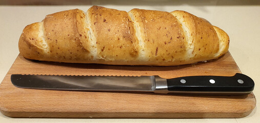 Freshly baked homemade bread with a knife on a cutting board close-up