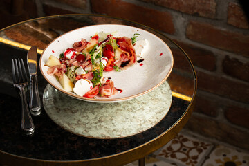 Prosciutto crudo ham salad with mozzarella cheese and arugula on a plate. Bright background. Top view. Copy space