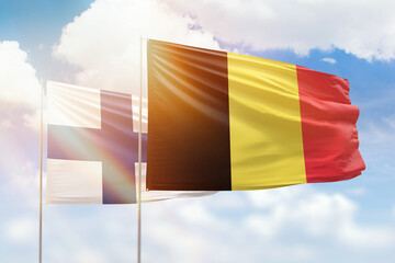 Sunny blue sky and flags of belgium and finland