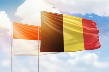 Sunny blue sky and flags of belgium and indonesia
