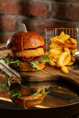 Big cheeseburger with french fries. Hamburger with beef patty onion, tomato, lettuce pickles, melted cheddar, mustards, tomato jam, mayo