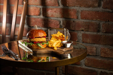Big cheeseburger with french fries. Hamburger with beef patty onion, tomato, lettuce pickles, melted cheddar, mustards, tomato jam, mayo
