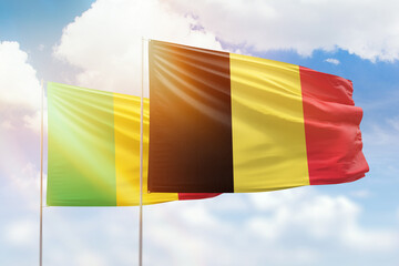 Sunny blue sky and flags of belgium and mali