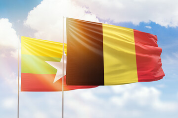 Sunny blue sky and flags of belgium and myanmar