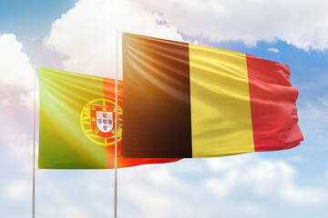 Sunny blue sky and flags of belgium and portugal