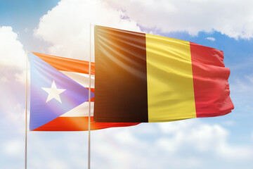 Sunny blue sky and flags of belgium and puerto rico