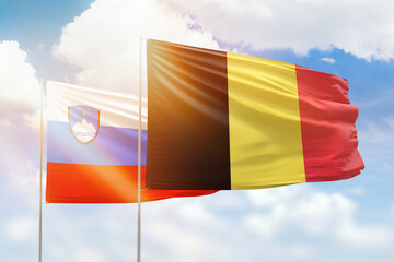 Sunny blue sky and flags of belgium and slovenia