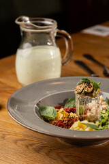 Closeup of cold soup okroshka with beef, vegetables and kefir served in a white bowl, selective focus. Summer, cold soup with cucumber, radish, egg, potatoes and fresh herbs seasoned with kefir.