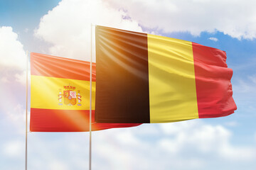 Sunny blue sky and flags of belgium and spain