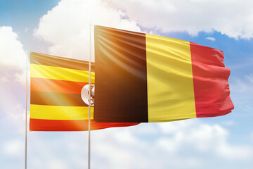 Sunny blue sky and flags of belgium and uganda