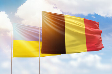Sunny blue sky and flags of belgium and ukraine