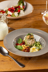 Closeup of cold soup okroshka with beef, vegetables and kefir served in a white bowl, selective focus. Summer, cold soup with cucumber, radish, egg, potatoes and fresh herbs seasoned with kefir.