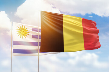 Sunny blue sky and flags of belgium and uruguay