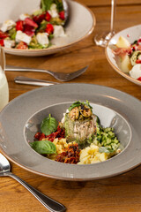 Closeup of cold soup okroshka with beef, vegetables and kefir served in a white bowl, selective focus. Summer, cold soup with cucumber, radish, egg, potatoes and fresh herbs seasoned with kefir.