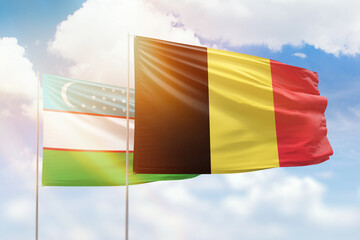 Sunny blue sky and flags of belgium and uzbekistan