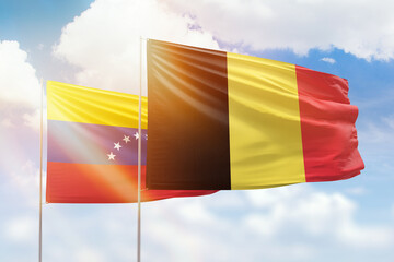 Sunny blue sky and flags of belgium and venezuela