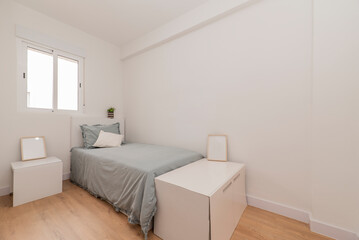 Bedroom with a small bed with a blue bedspread, white furniture and a cherry wood floor