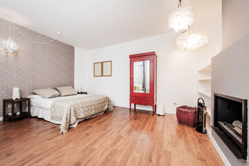 Double room decorated with wallpaper, red painted wardrobe with mirror, double bed and wood burning fireplace