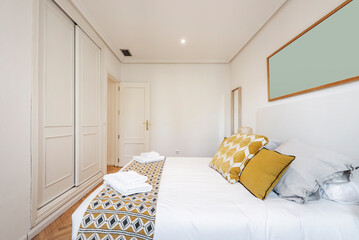 Vacation rental apartment with a double bed with a white duvet, matching blanket and cushions and a...