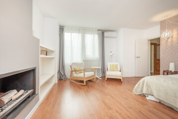 Double bedroom decorated with wallpaper, wooden rocking chairs and white cushions, double bed and wood burning fireplace