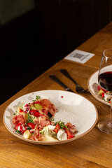 Prosciutto crudo ham salad with mozzarella cheese and arugula on a plate. Bright background. Top view. Copy space