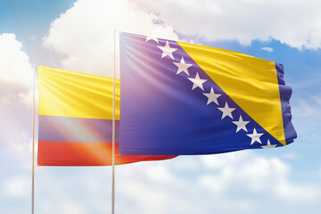 Sunny blue sky and flags of bosnia and colombia