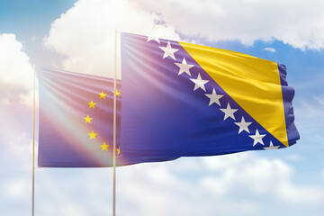 Sunny blue sky and flags of bosnia and european union