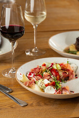 Prosciutto crudo ham salad with mozzarella cheese and arugula on a plate. Bright background. Top view. Copy space