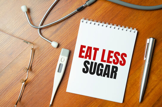 eat less sugar words on notebook and stethoscope on wooden background