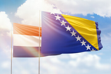 Sunny blue sky and flags of bosnia and netherlands