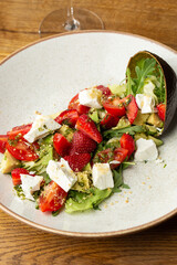 Tasty and healthy salad with arugula, brie cheese, avocado, cherry tomatoes and strawberry. Top view. The flat lay. Banner