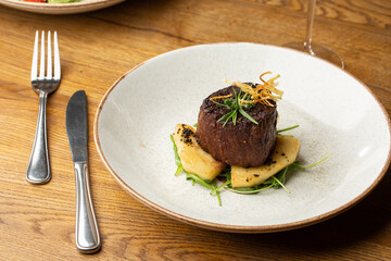 Grilled meat fillet steak medallion with green sauce, served with pear or apple. On dark background