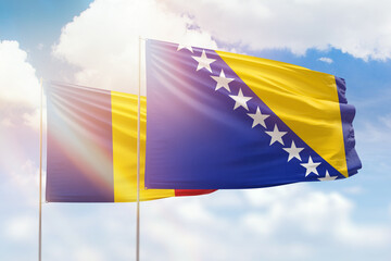 Sunny blue sky and flags of bosnia and romania