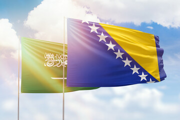 Sunny blue sky and flags of bosnia and saudi arabia