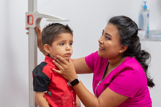 Close Up Of A Female Pediatrician Doctor Measuring A Child's Height With A Pedestal Ruler