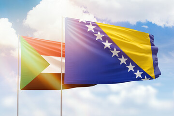 Sunny blue sky and flags of bosnia and sudan