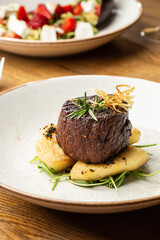 Grilled meat fillet steak medallion with green sauce, served with pear or apple. On dark background