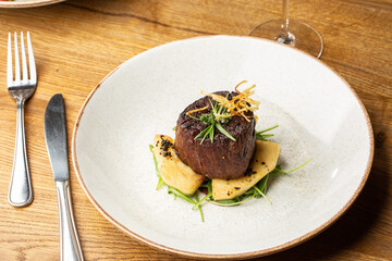 Grilled meat fillet steak medallion with green sauce, served with pear or apple. On dark background