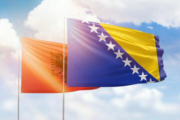 Sunny blue sky and flags of bosnia and albania