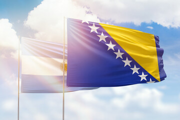 Sunny blue sky and flags of bosnia and argentina
