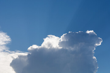 A big rain cloud and the sun rays break through behind the clouds on a summer day. Close up and...
