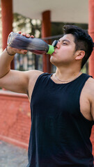 Fototapeta na wymiar Muscular latin man drinking energy drink in a park, lifestyle. 