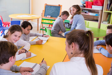 Obraz premium Young female teacher and pupils working in classroom at elementary school