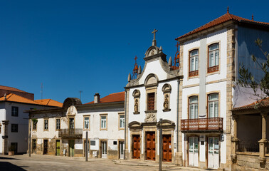 Fototapeta na wymiar View of residential houses and ancient Church of Mercy on typical paved street in old town of Mirandela in spring, Portugal..