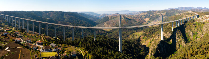 Picturesque panoramic aerial view of high modern suspension viaduct with highway crossing rocky...