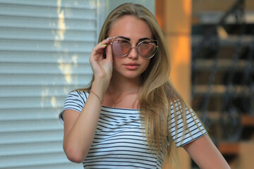 beautiful fashionable blond girl in the city on the park in dress and glasses at summer