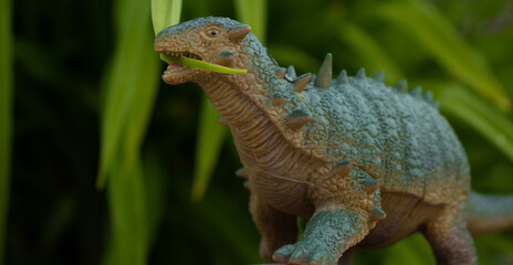 An armored Pinacosaurus chews on a green leaf as it wanders through vegetation. 