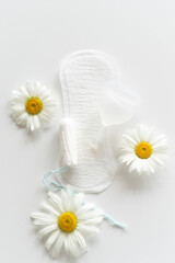 Obraz premium Menstruation period concept. Hygienic white female pad, Menstrual cup and tampon with chamomile flowers. Menstruation, protection. Women's health