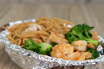 Delicious basket of grilled shimp and chow mein noodles with vegetables for a tasty seafood meal