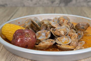 Delicious boiled pallet of clams, corn on the cobb, and potatoes in a buttery sauce for a tasty seafood meal